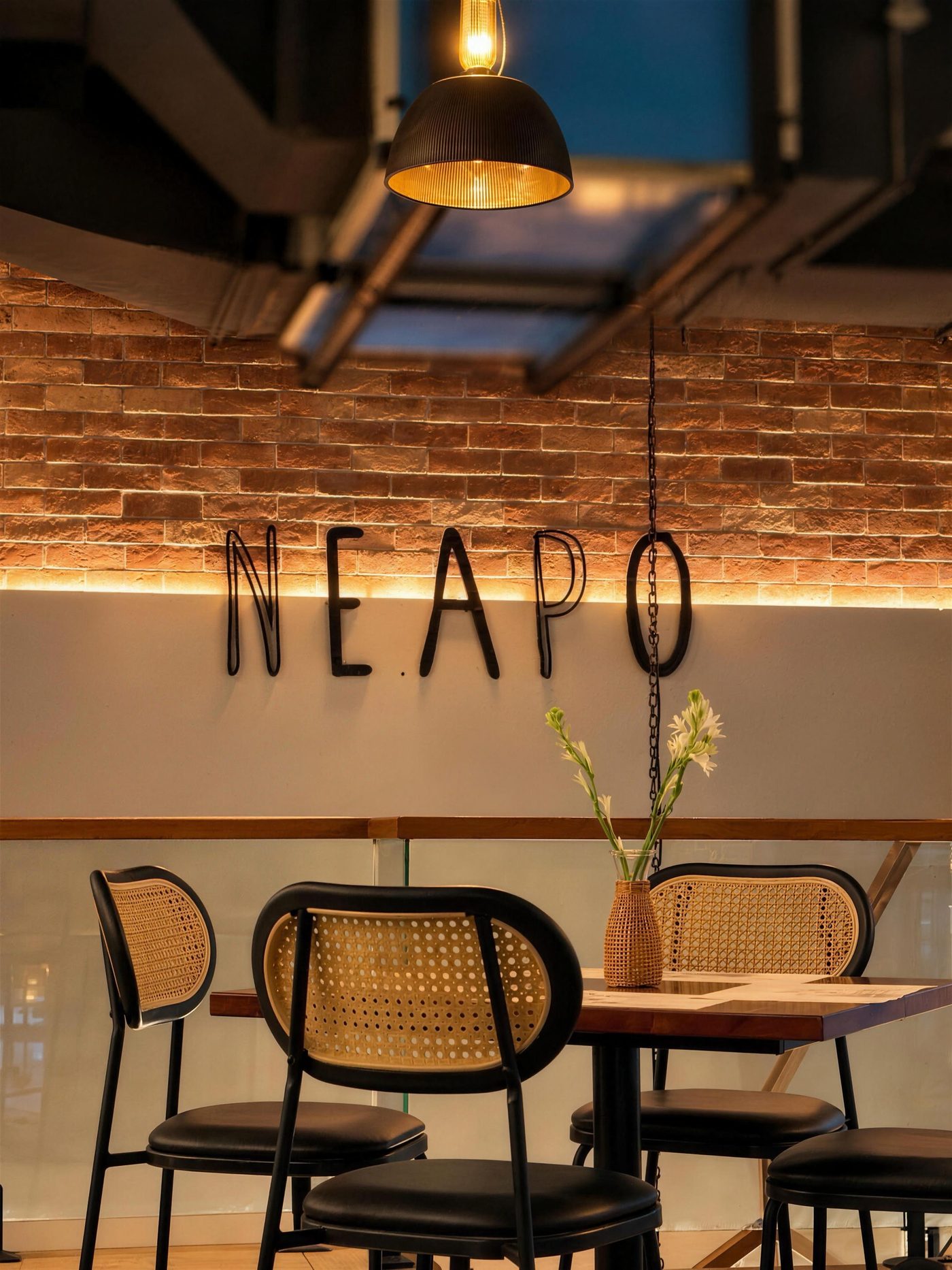 Inside Neapo: brick wall, warm pendant light and rattan chairs