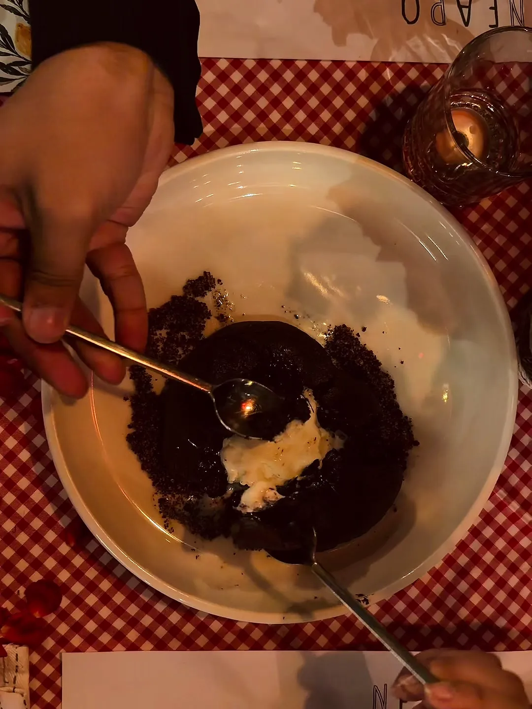 Two spoons sharing a chocolate fondant with vanilla ice cream
